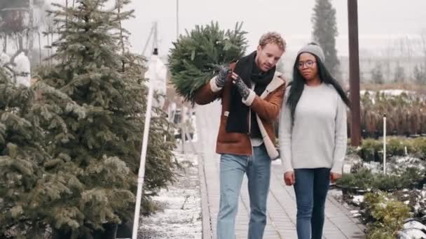 ヨーロッパの男性とアフリカ系アメリカ人の女性がクリスマスツリーを買った — ストック動画