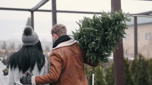 Uomo europeo e donna afro-americana che trasportano comprato albero di Natale — Video Stock
