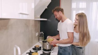 Mutlu genç çift evde kahvaltı hazırlarken mutfakta sarılıp sohbet ediyorlar.