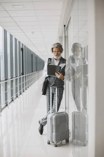 Starszy biznesmen z walizką podróżną na lotnisku — Zdjęcie stockowe