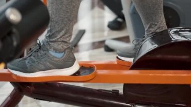 Orta yaşlı şişman kadın spor salonunda elips makinesi kullanıyor.