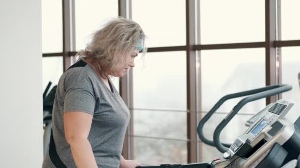 Donna in sovrappeso che si allena su un tapis roulant in palestra — Video Stock
