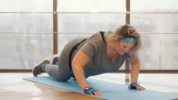 Избыточный вес женщина делает упражнения на мат в тренажерном зале — стоковое видео