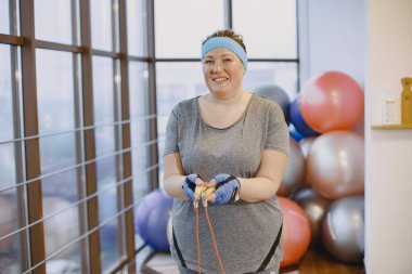 Yetişkin şişman kadın spor salonunda jimnastik yapıyor.