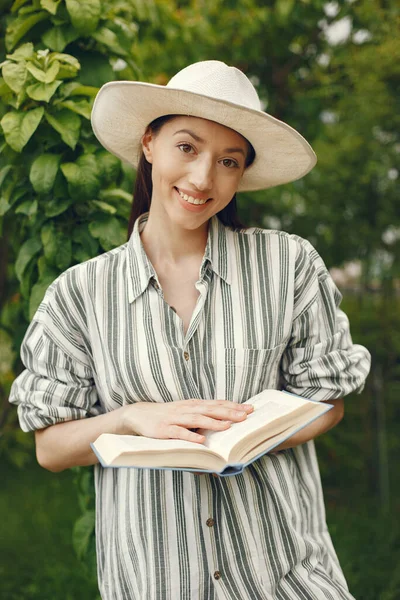 Mulher de chapéu com livro em jardim — Fotografia de Stock