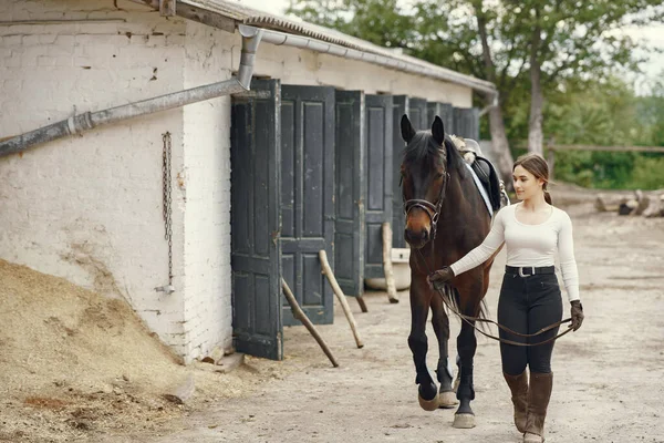 Elegant flicka på en gård med en häst — Stockfoto