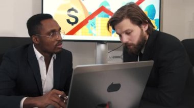 Takım elbiseli iki işadamı ofiste tartışıyorlar.