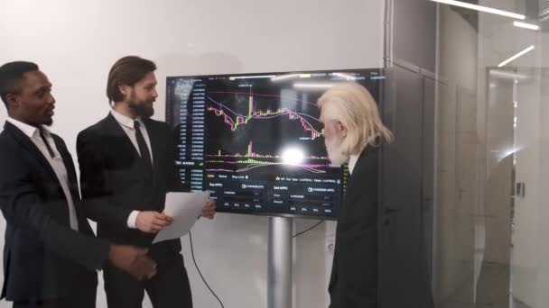 Les hommes d'affaires vérifient le marché boursier sur le tableau numérique — Video