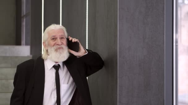 Volwassen man in pak in gesprek op mobiele telefoon op kantoor — Stockvideo