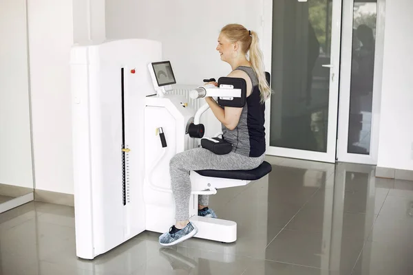 Junge Dame macht Übungen am Simulator im Physiotherapieraum — Stockfoto