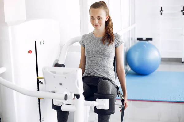 Junge Dame macht Übungen am Simulator im Physiotherapieraum — Stockfoto