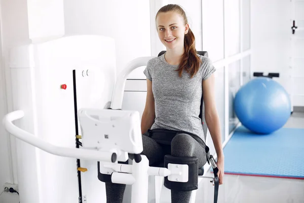 Junge Dame macht Übungen am Simulator im Physiotherapieraum — Stockfoto