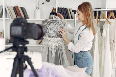 Tasarımcı kıyafet yapar ve kameraya çeker.