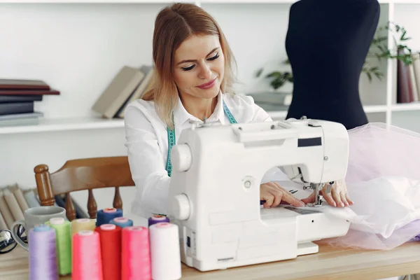 Kobieta siedzi w studio i szyje tkaniny — Zdjęcie stockowe