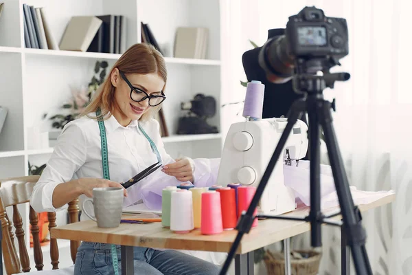 Жінка сидить в студії і шиє тканину — стокове фото