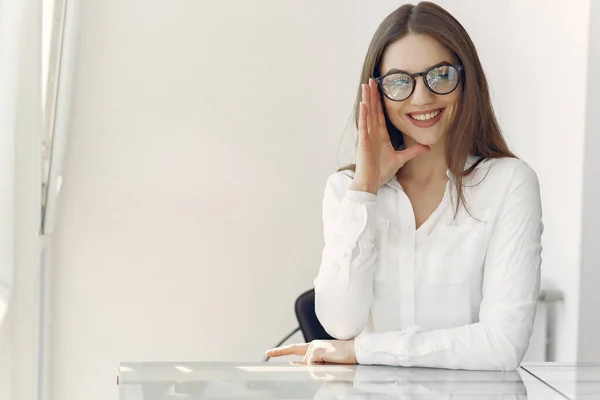 Zakenvrouw in een wit shirt zittend op kantoor — Stockfoto