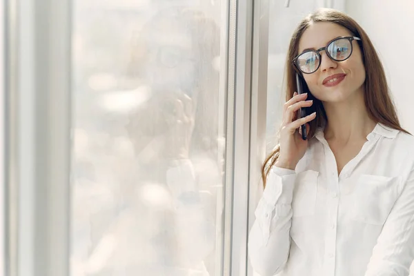 Dívka stojící v kanceláři s telefonem — Stock fotografie