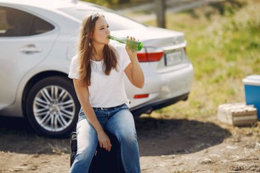 Arabanın yanında duran zarif kadın.