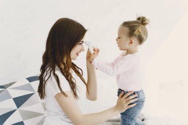 Termometresi olan anne kızının yanında oturuyor.