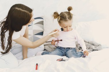 Anne kızıyla yatakta kozmetikle oynuyor.