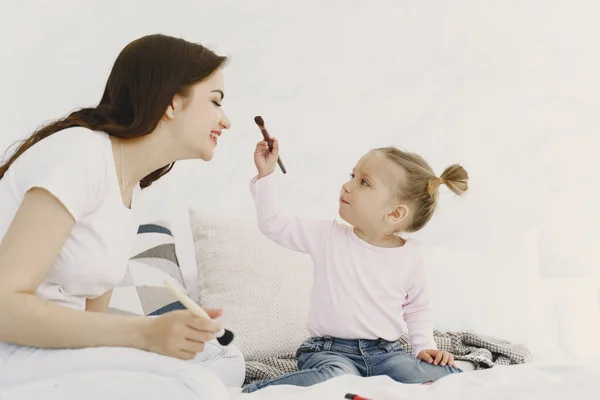 Mãe brincando com cosméticos na cama com sua filha — Fotografia de Stock