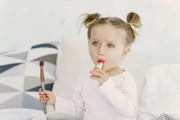 Menina bonita com cosméticos de maquiagem em casa — Fotografia de Stock