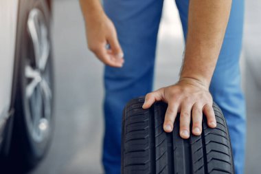 Mavi üniformalı yakışıklı adam arabayı kontrol ediyor.