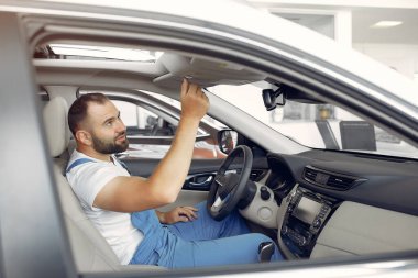 Mavi üniformalı yakışıklı adam arabayı kontrol ediyor.