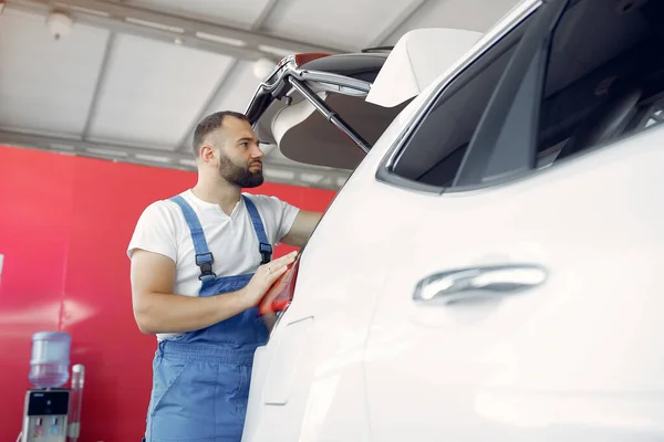 Handsome man in a blue uniform checks the car — Stock Photo, Image