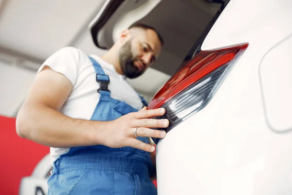 Hombre guapo con uniforme azul comprueba el coche —  Fotos de Stock