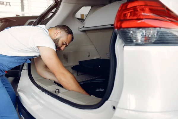 Hombre guapo con uniforme azul comprueba el coche —  Fotos de Stock