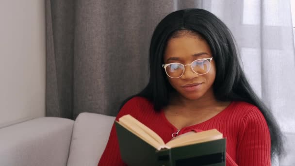 Donna afroamericana che legge un libro seduta sul letto di casa — Video Stock