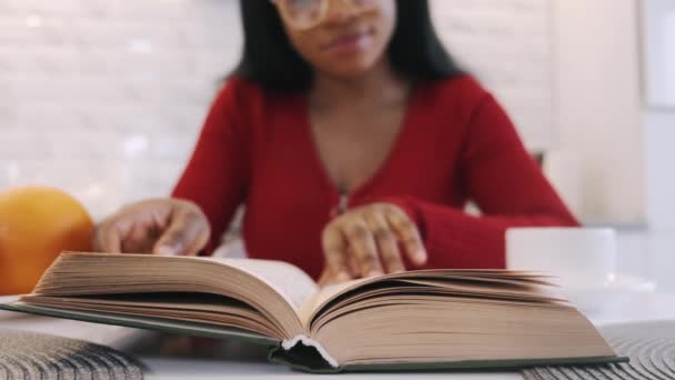 Menina afro-americana bebendo café e estudando em casa na cozinha — Vídeo de Stock