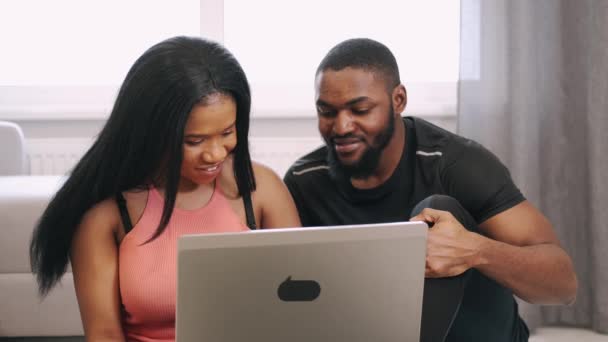 Sportig afrikansk amerikansk par använda laptop innan träning — Stockvideo