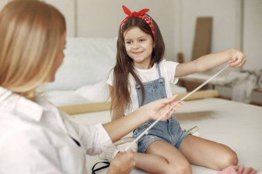 Annesi ve kızı dikiş dikmek için kumaşı ölçüyorlar.