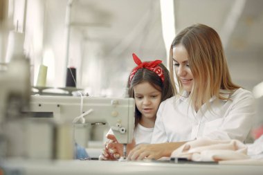 Annesi ve küçük kızı fabrikada dikiş dikiyor.