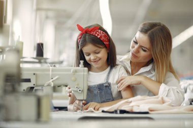 Annesi ve küçük kızı fabrikada dikiş dikiyor.