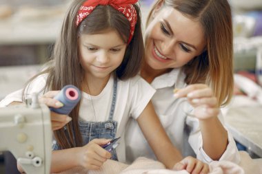 Annesi ve küçük kızı fabrikada dikiş dikiyor.