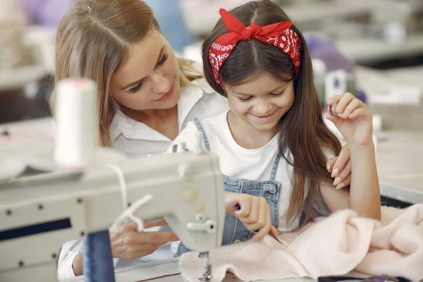 Mutter mit kleiner Tochter näht Kleidung in der Fabrik — Stockfoto