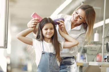 Anne ve küçük kızı iplikle kumaşın başında duruyor.