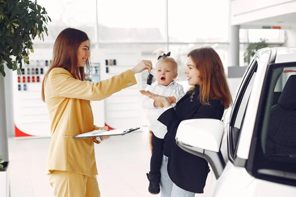 Mujer elegante con hija pequeña en un salón de coches — Foto de Stock