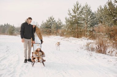 Kış giysileri içindeki aile, kış ormanlarında oynar.