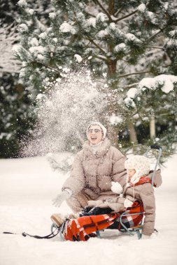 Anne ve çocuk kışın bahçede oynuyorlar.