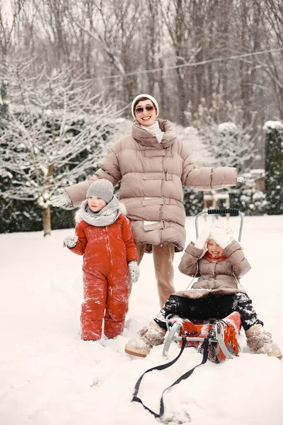Мать и дети в зимней одежде играют на заднем дворе — стоковое фото