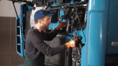 Profesyonel araba tamircisi araba garajındaki kamyon motorunu kontrol ediyor.