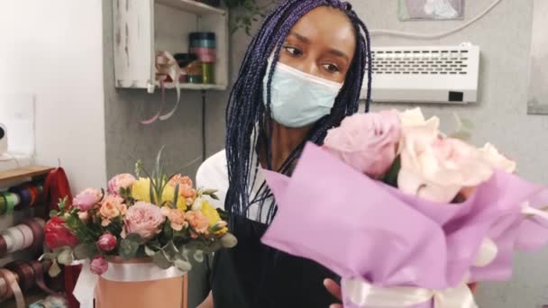 Donna afroamericana fiorista in maschera che tiene due mazzi di fiori — Video Stock