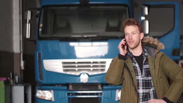 Motorista falando por telefone em pé na garagem de serviço de caminhão — Vídeo de Stock