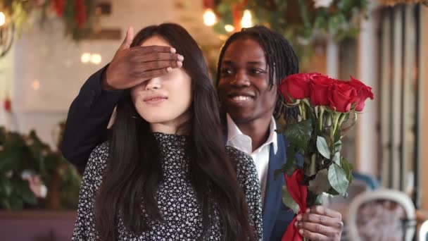 Hombre africano haciendo sorpresa para su novia el día de San Valentín en el restaurante — Vídeo de stock