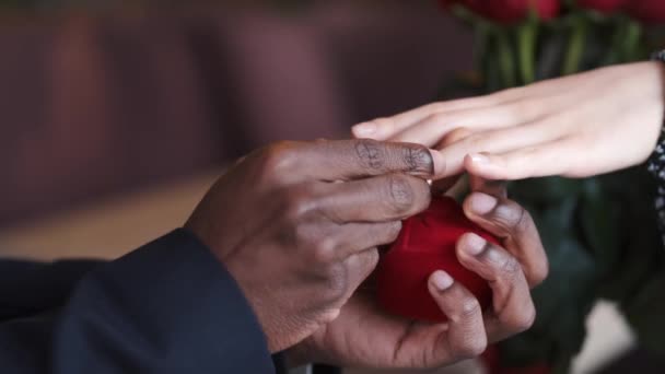 Primer plano de hombre afro poniendo anillo en dedo de mujer — Vídeos de Stock