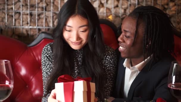 African man with Corean woman unpacking present at restaurant — Stock Video